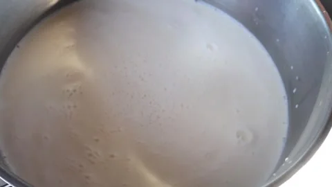 Milk bubbling and rotating while heating Stock Footage 322811588