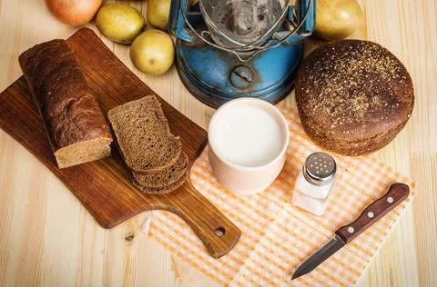 Milk in ceramic ware, rye bread, cutting board, salt and salt salt, onions Stock Photos