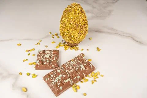 Milk chocolate bar and Easter egg with pistachio pieces. Stock Photos