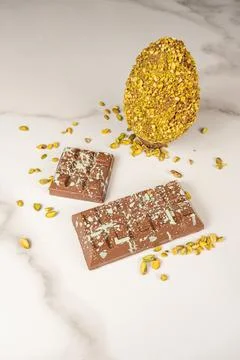 Milk chocolate bar and Easter egg with pistachio pieces vertical. Stock Photos