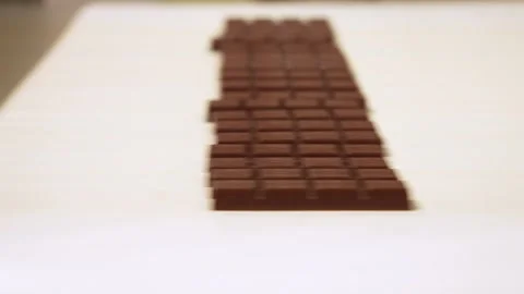 Milk chocolate bars move along a white industrial conveyor belt Stock Footage 323354826