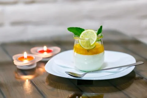 Milk dessert with lime at the table by candlelight Foto stock