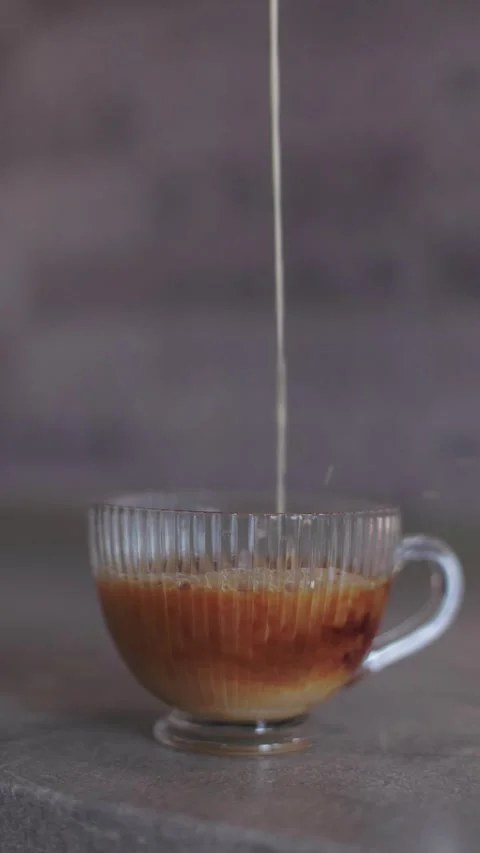 Milk diffusion in black tea, glass cup close-up, vertical 4K Stock Footage 328352651
