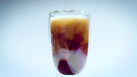 Milk dissolves in coffee or tea drink. glass with double walls on white Stock Footage 161184674