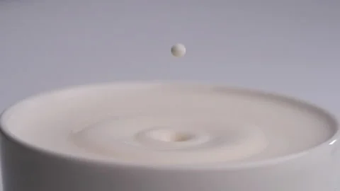 Milk drop falls into the filled cup created ripple wave in slow motion. Stock Footage 144680110