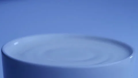 Milk drop falls into the filled cup created ripple wave in slow motion. Stock-Footage 144680136