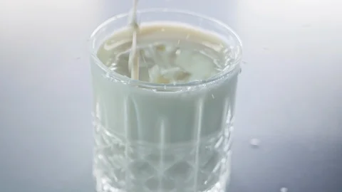 Milk drops falling into small crystal glass in slow motion Stock Footage 125589434