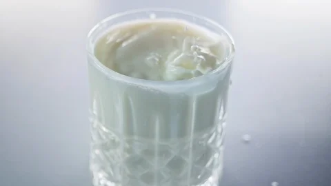 Milk drops falling into small crystal glass in slow motion Stock Footage 125589654