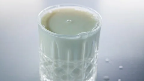 Milk drops falling into small crystal glass in slow motion Stock Footage 125589797
