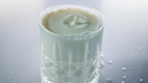 Milk drops falling into small crystal glass in slow motion Video stock 125589915