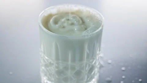 Milk drops falling into small crystal glass in slow motion Stock Footage 125590043
