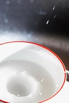 Milk drops - milk drop into small cup with milk Stock Photos
