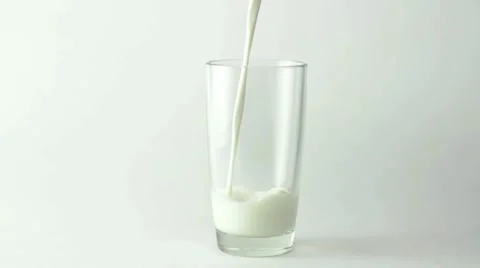 Milk filling the glass over white background Stock Footage