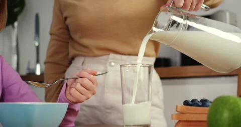 Milk flows in slow-motion close-up for daughter by caring mom Healthy family Stock Footage 259726253