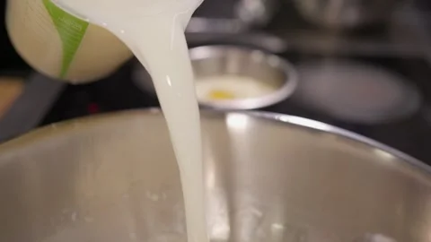 Milk flows into sweet foamy egg mixture creating base for dough preparation Stock-Footage 324196327