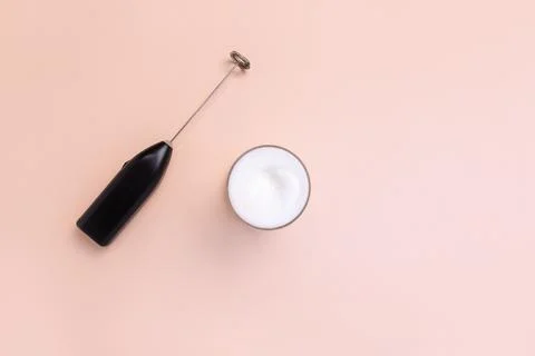 Milk foam maker with glass of milk on pink peach background. Stock Photos