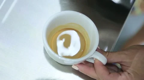 Milk with foam is poured into the cup of coffee Stock Footage 63144887