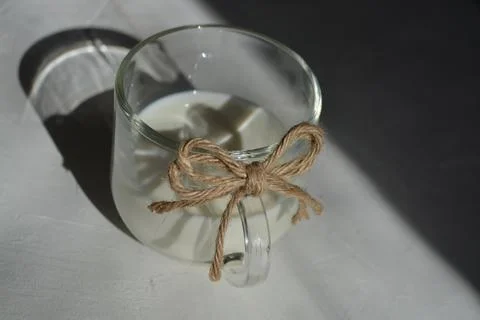 Milk in a glass with a bow of string. on a gray background with a hard light. Stock Photos