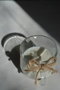 Milk in a glass with a bow of string. on a gray background with a hard light Stock Photos