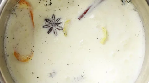 Milk mixture bubbles with orange zest, lemon peel, cinnamon and vanilla. Stock Footage 345273468