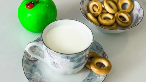 Milk in a mug on the table with bread, drying or apples Stock Photos