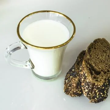 Milk in a mug on the table with bread, drying or apples Foto stock