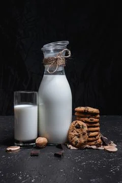 Milk placed on table with stack of chocolate chip cookies Stock Photos