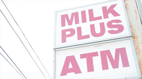 Milk plus atm white red sign protruding from building exterior outside writing Stock Footage 252043463