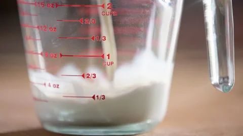 Milk pour into measuring cup to one cup level in slow motion Stock Footage 304187616