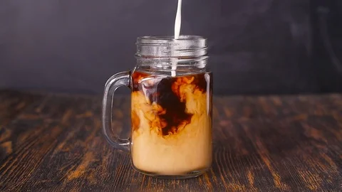 Milk is poured into coffee Stock Footage 77340276