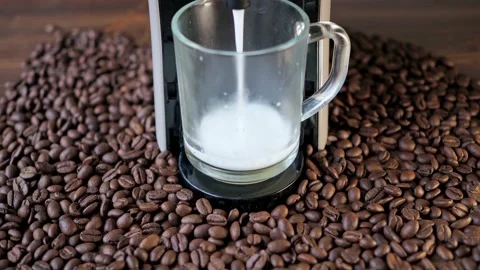 Milk is poured from a coffee machine. there are coffee beans on the table Stock Footage 166737524