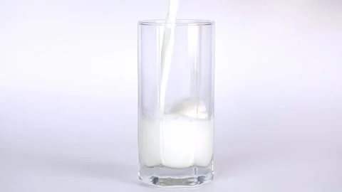 Milk is poured on a light background with a transparent glass Stock-Footage 196372604