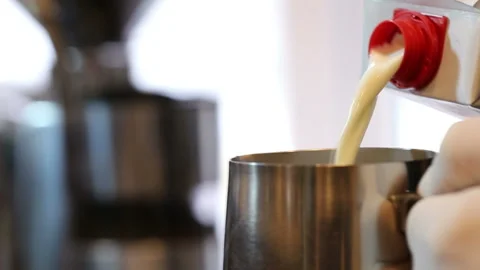 Milk is poured into a metal bowl in slow motion Stock Footage