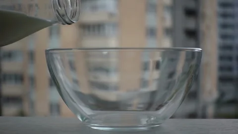 Milk is poured in slow motion from a bottle into a  bowl Stock Footage 131042020