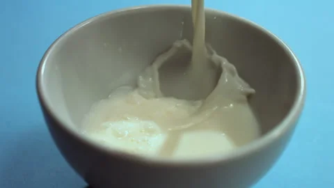 Milk poured slowly into the cup Stock Footage 274210858