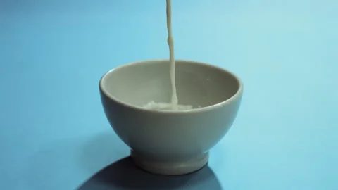 Milk poured slowly into the cup Stock Footage 274214382