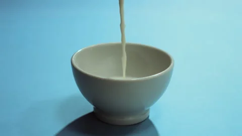 Milk poured slowly into the cup Stock Footage 274215152