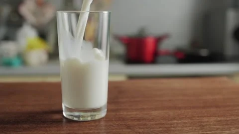 Milk is Poured into Transparent Glass The camera Moves Around the Table Stock Footage