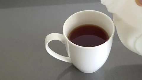 Milk poured into a white mug of tea Stock Footage 244925636