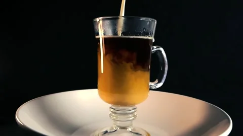 Milk pouring into coffee cup in slow motion on black background Stock Footage 340148315