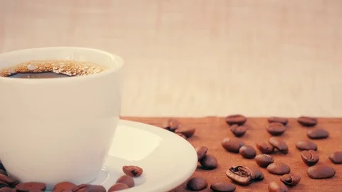 Milk pouring into Hot Coffee cup on a wooden table with coffee beans Vídeo Stock 80998720