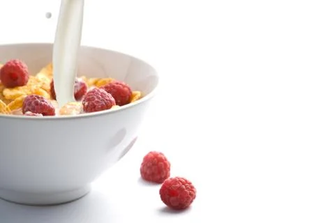 Milk pouring onto muesli with raspberry isolated Stock Photos