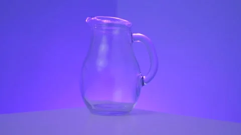 Milk pouring into small jug in front of purple background in slow motion Stock Footage 130979997