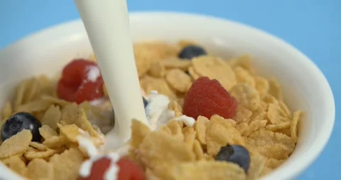 Milk pouring with splash into cornflakes with berry breakfast cereal Stock Footage 342591212