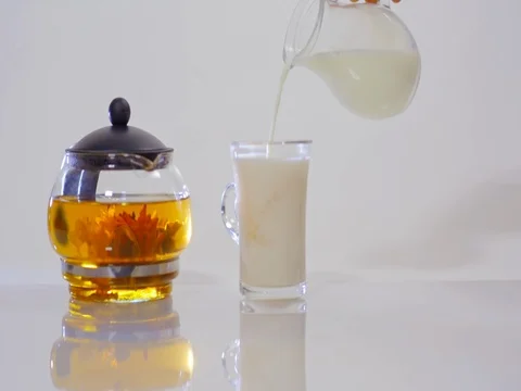 Milk pouring into tea in a transparent Cup Stock Footage 73954388
