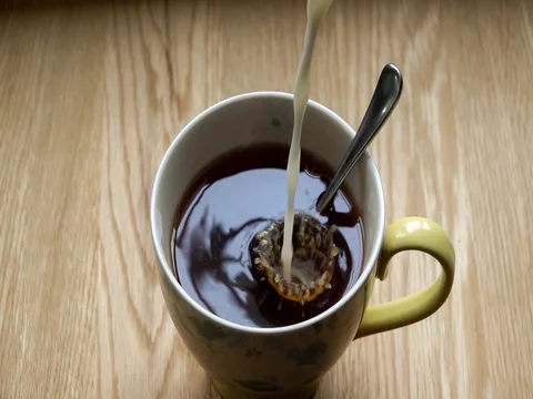 Milk pours into black coffee in slow motion Stock Footage 80316470
