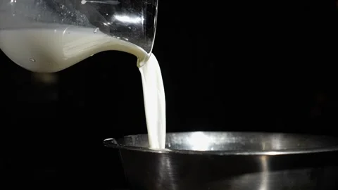 Milk pours from a pitcher against a dark background. Preparing the dough. Stock Footage 264404824