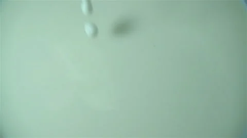 Milk pours in slow motion onto the surface of the milk Stock Footage 121199421