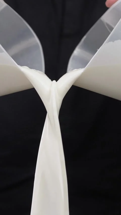 Milk pours in a stream from a measuring cup on a black background. Stock Footage 281667476
