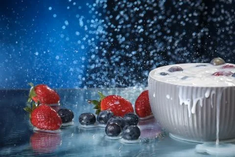 Milk splash close up of falling berries in a grey plate of milk. Stock Photos